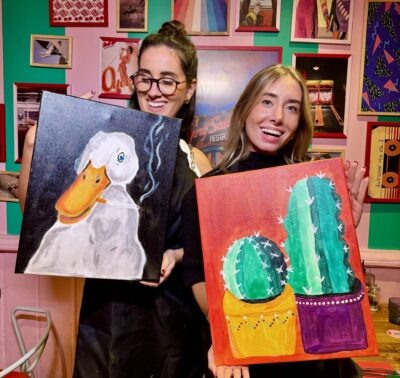 Deux participantes souriantes posent avec leurs tableaux colorés après un atelier apéro peinture à Paris
