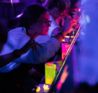 Femme en train de peindre avec de la peinture fluorescente lors d’un atelier Glow in the Dark à Paris