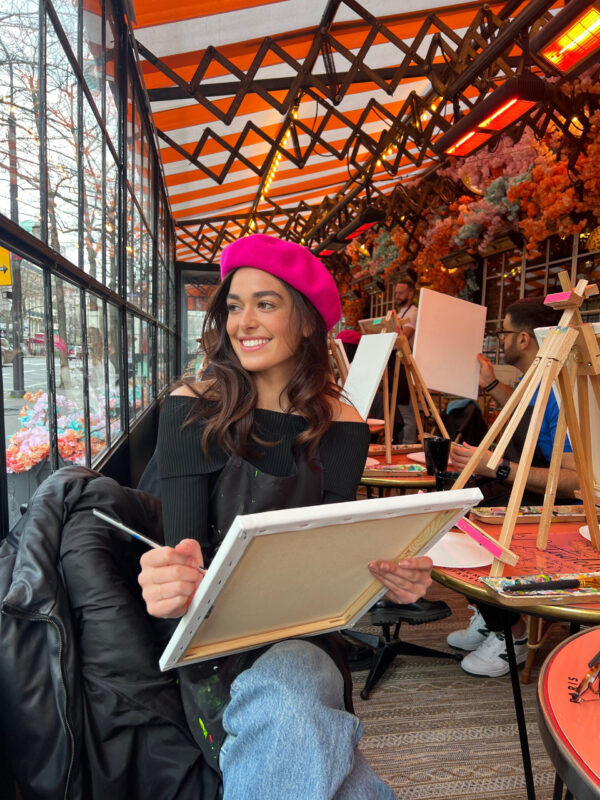 Jeune femme souriante participant à un atelier peinture et petit déjeuner à Paris dans une ambiance conviviale et artistique
